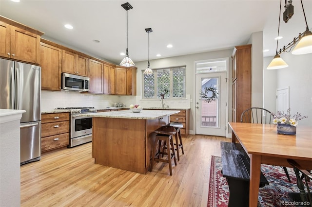3240 Spruce St, Denver, CO 80238 - kitchen featuring appliances with stainless steel finishes, light wood-style flooring, brown cabinets, decorative backsplash, and a kitchen island