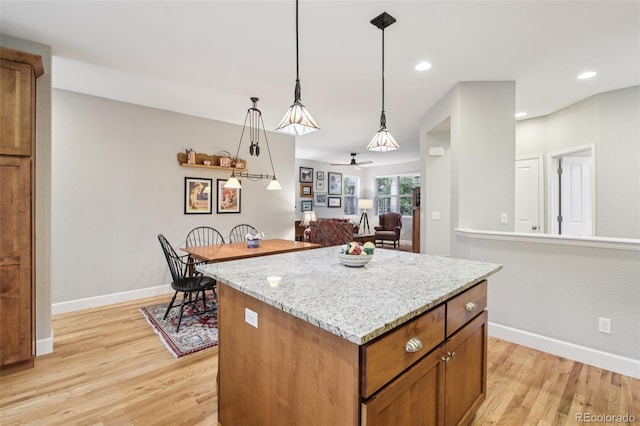 3240 Spruce St, Denver, CO 80238 - kitchen with light wood-style flooring, a kitchen island, decorative light fixtures, brown cabinetry, and light stone countertops
