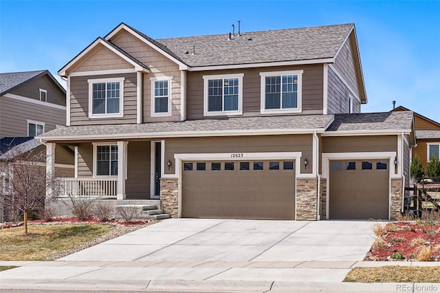 12623 Canoe St, Firestone, CO 80504 - view of front facade with covered porch, concrete driveway, an attached garage, and stone siding
