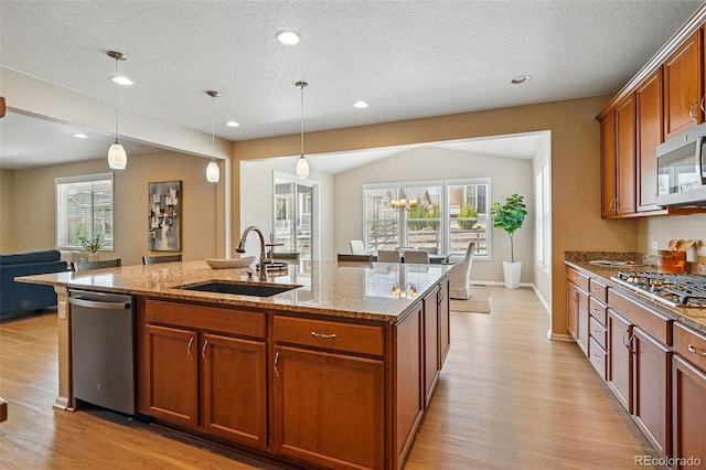 12623 Canoe St, Firestone, CO 80504 - kitchen featuring appliances with stainless steel finishes, light wood-style flooring, open floor plan, light stone countertops, and a textured ceiling