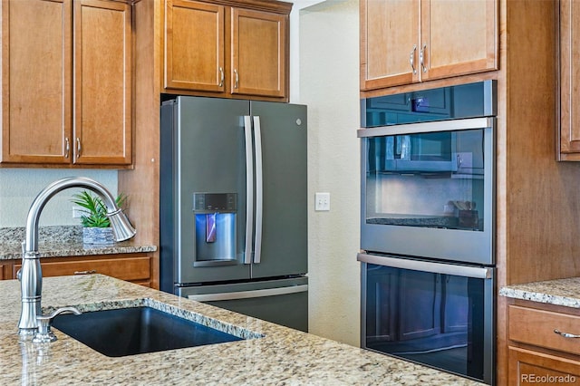 12623 Canoe St, Firestone, CO 80504 - kitchen with appliances with stainless steel finishes, light stone counters, and brown cabinetry