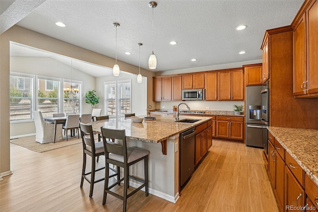 12623 Canoe St, Firestone, CO 80504 - kitchen with appliances with stainless steel finishes, brown cabinets, light wood-style flooring, lofted ceiling, and a textured ceiling