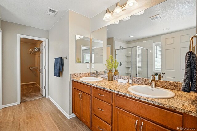 12623 Canoe St, Firestone, CO 80504 - full bath featuring a shower stall, wood finished floors, double vanity, a textured ceiling, and a spacious closet