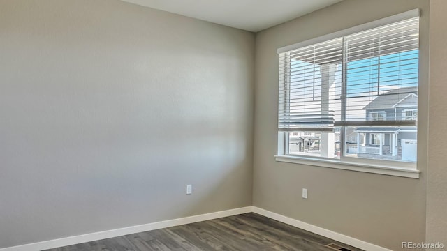 empty room featuring a wealth of natural light and dark hardwood / wood-style flooring