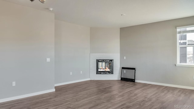 unfurnished living room with hardwood / wood-style floors and a multi sided fireplace