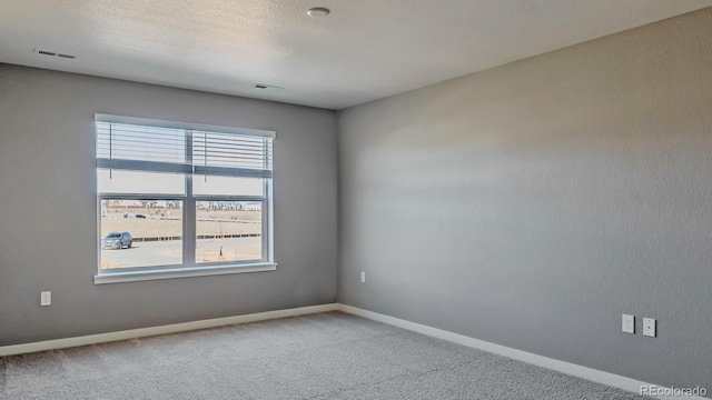 carpeted empty room featuring a textured ceiling