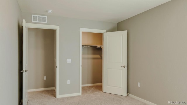 unfurnished bedroom with a walk in closet, light colored carpet, and a closet