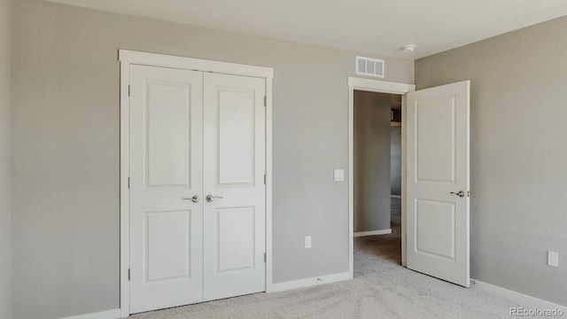 unfurnished bedroom featuring light carpet and a closet