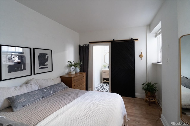 bedroom featuring baseboards, a barn door, and wood finished floors