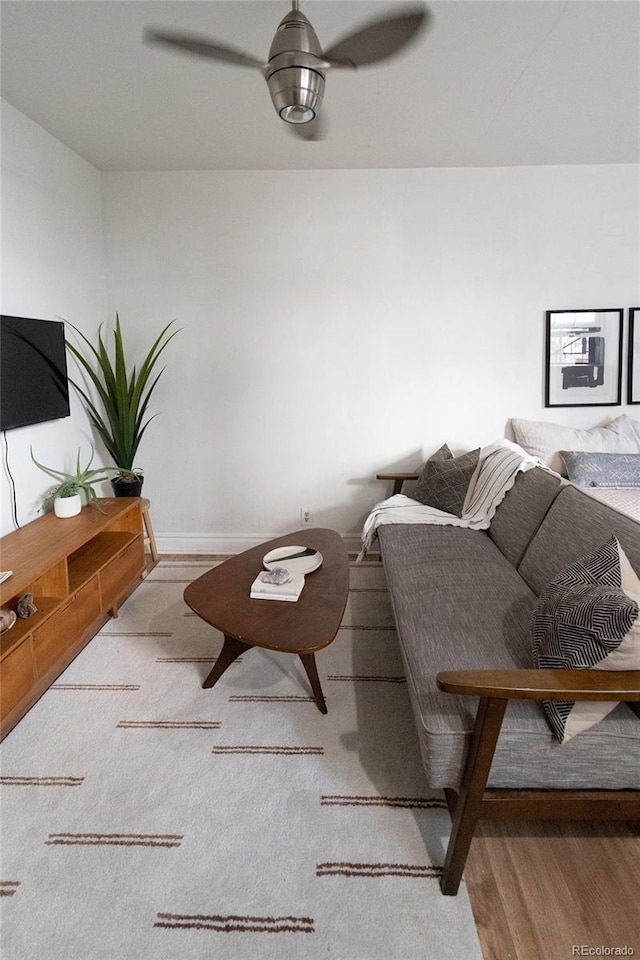 living room featuring baseboards, wood finished floors, and ceiling fan