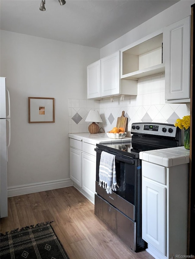 kitchen with tile countertops, freestanding refrigerator, tasteful backsplash, and stainless steel electric range