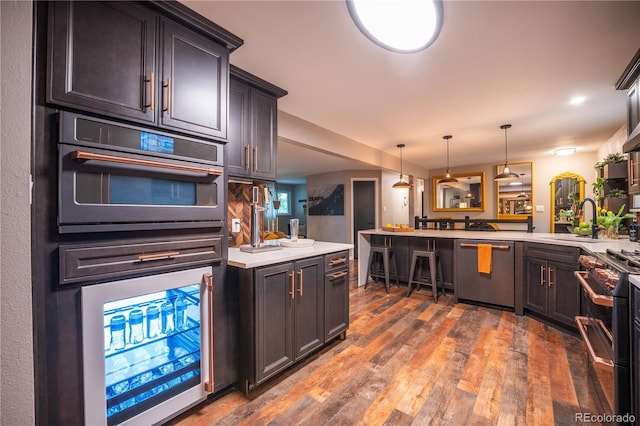 3125 Xenon St, Wheat Ridge, CO 80215 - kitchen featuring appliances with stainless steel finishes, a peninsula, light countertops, and hardwood / wood-style flooring