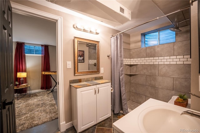 3125 Xenon St, Wheat Ridge, CO 80215 - bathroom featuring a tile shower, vanity, plenty of natural light, and baseboards