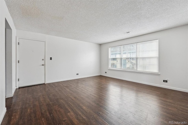 empty room with dark hardwood / wood-style floors and a textured ceiling