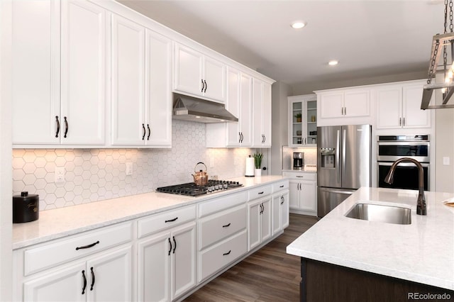 kitchen with backsplash, appliances with stainless steel finishes, sink, and white cabinetry