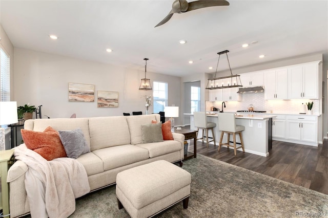 living room featuring ceiling fan and dark hardwood / wood-style floors