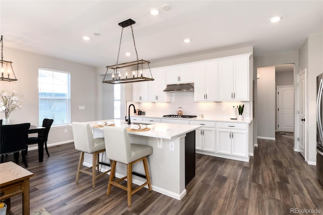 kitchen featuring white cabinetry, dark hardwood / wood-style flooring, an island with sink, hanging light fixtures, and gas cooktop