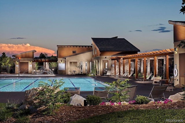 pool at dusk featuring a pergola and a patio area