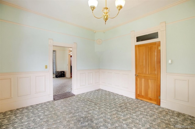 carpeted empty room featuring crown molding and a chandelier