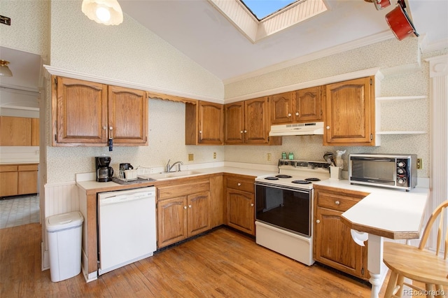 kitchen featuring a skylight, sink, light hardwood / wood-style flooring, high vaulted ceiling, and white appliances