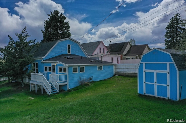 back of property featuring a wooden deck, a yard, and a shed