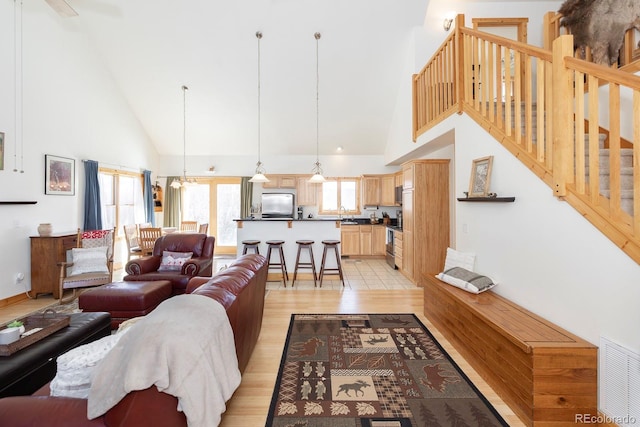 living room featuring an inviting chandelier, light hardwood / wood-style floors, and high vaulted ceiling