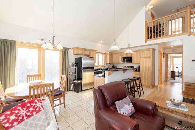 living room featuring an inviting chandelier, light hardwood / wood-style floors, high vaulted ceiling, and sink