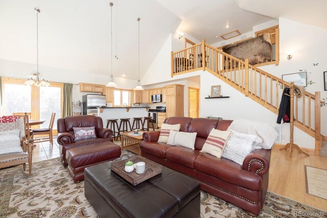 living room featuring an inviting chandelier, high vaulted ceiling, and light hardwood / wood-style flooring