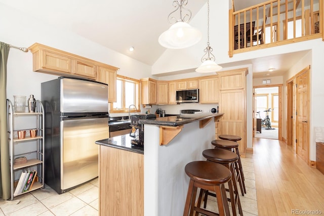 kitchen with stainless steel appliances, decorative light fixtures, light hardwood / wood-style flooring, a kitchen island, and lofted ceiling