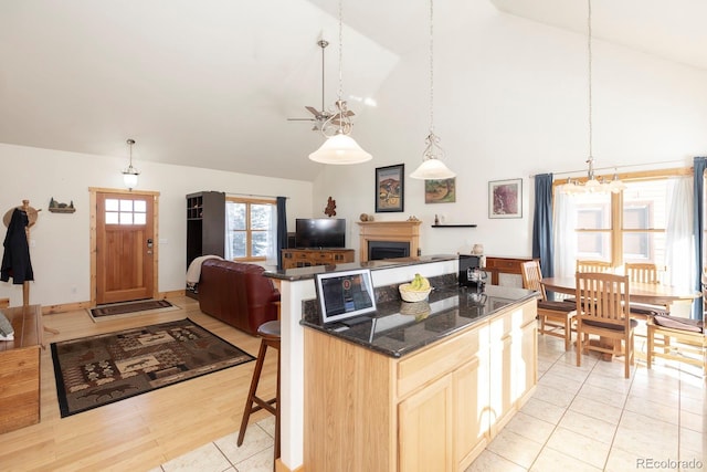 kitchen featuring a kitchen bar, light brown cabinetry, decorative light fixtures, light hardwood / wood-style flooring, and a center island