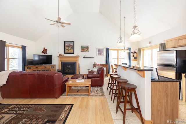 living room featuring high vaulted ceiling, ceiling fan, and light tile patterned flooring