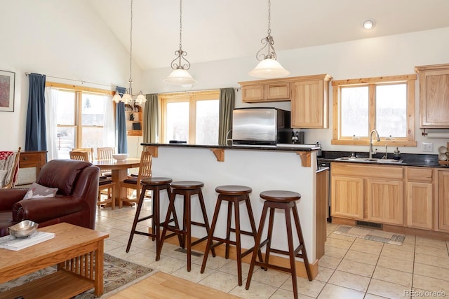 kitchen featuring plenty of natural light, stainless steel refrigerator, sink, and hanging light fixtures