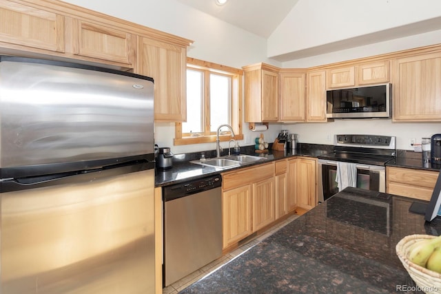 kitchen with light brown cabinets, sink, dark stone counters, lofted ceiling, and appliances with stainless steel finishes