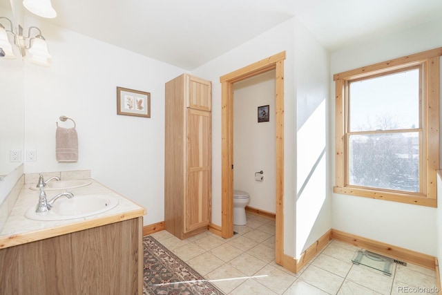 bathroom featuring double vanity, toilet, a sink, baseboards, and tile patterned floors