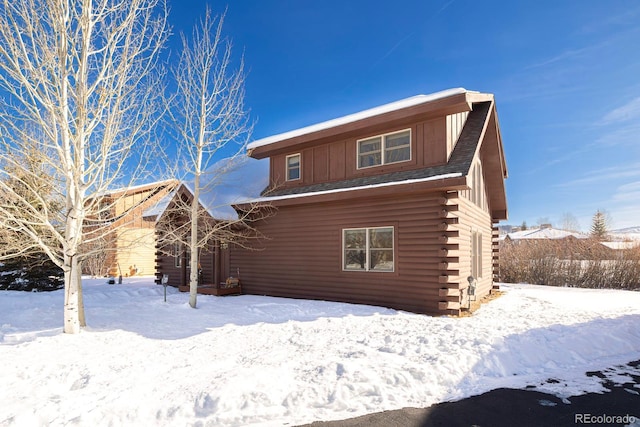 snow covered rear of property featuring log siding