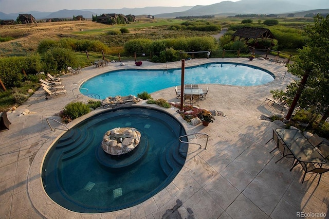 community pool featuring a community hot tub, a patio area, and a mountain view