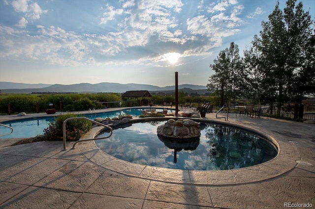 community pool featuring a patio, fence, and a mountain view