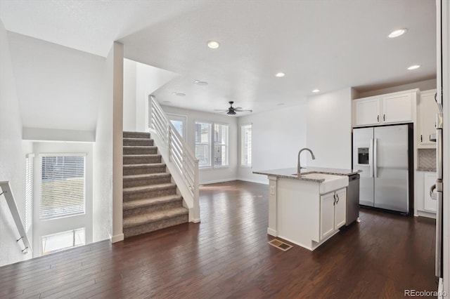 kitchen featuring dark wood-style floors, light stone countertops, a kitchen island with sink, a sink, and stainless steel appliances