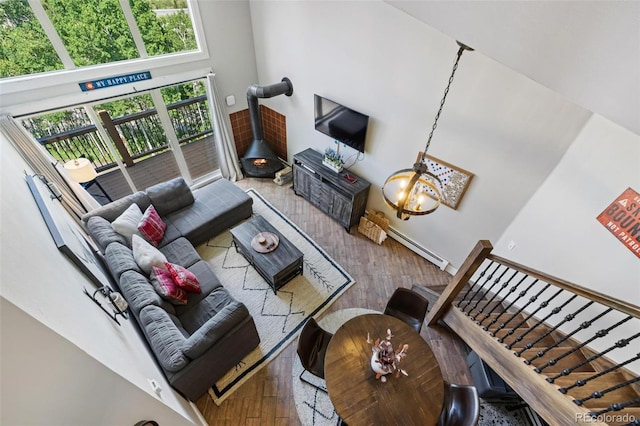 2449 Ryan Gulch Ct Unit 2449, Silverthorne, CO 80498 - living area with a wood stove, hardwood / wood-style floors, a baseboard radiator, and a towering ceiling