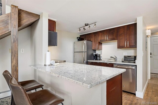 2449 Ryan Gulch Ct Unit 2449, Silverthorne, CO 80498 - kitchen with appliances with stainless steel finishes, light wood-type flooring, a kitchen bar, a peninsula, and a baseboard radiator