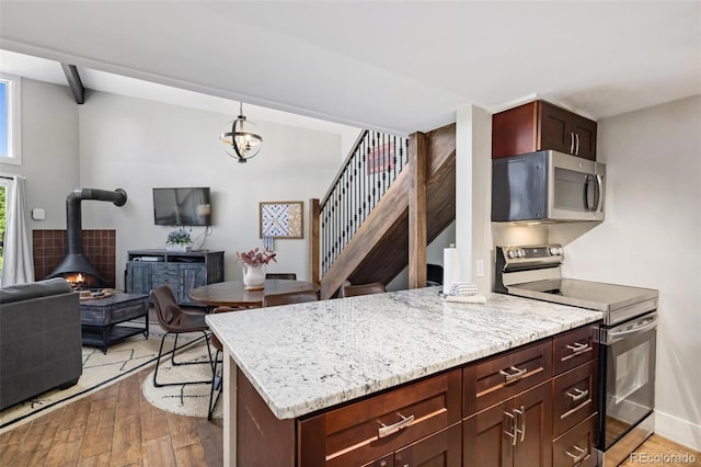 2449 Ryan Gulch Ct Unit 2449, Silverthorne, CO 80498 - kitchen featuring stainless steel appliances, hardwood / wood-style floors, open floor plan, a wood stove, and light stone counters