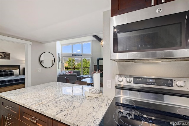 2449 Ryan Gulch Ct Unit 2449, Silverthorne, CO 80498 - kitchen with appliances with stainless steel finishes, light stone countertops, dark brown cabinetry, open floor plan, and a peninsula