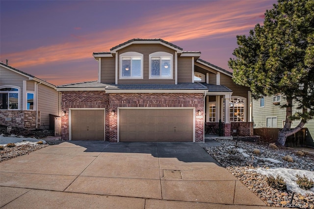 view of front of house with a garage, brick siding, driveway, and a tiled roof