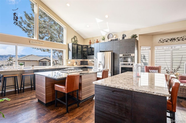 kitchen with a kitchen island, stainless steel appliances, dark wood finished floors, and a kitchen breakfast bar