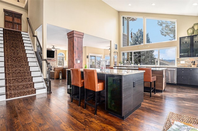 kitchen with a kitchen island, dark wood finished floors, a breakfast bar area, and a ceiling fan