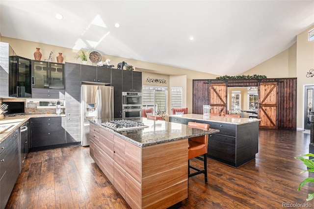 kitchen featuring a barn door, a breakfast bar area, appliances with stainless steel finishes, and a center island