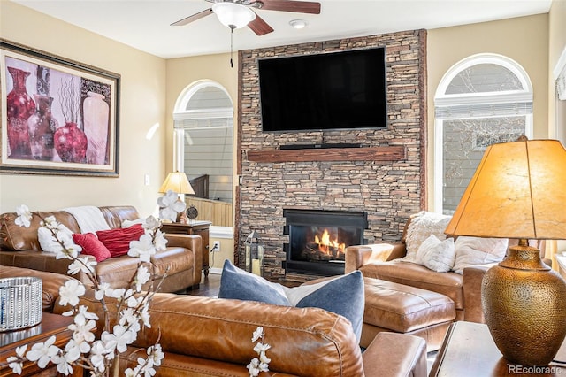 living area with a wealth of natural light, a fireplace, and ceiling fan