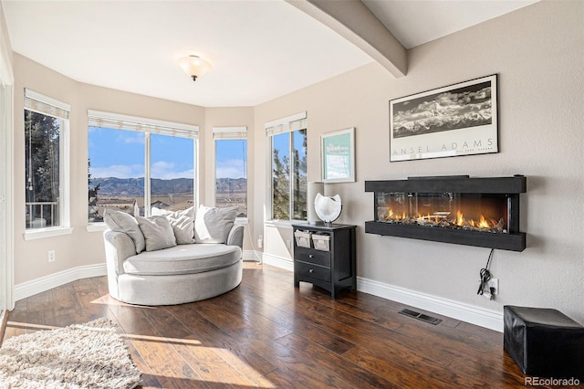 living area with hardwood / wood-style floors, a glass covered fireplace, visible vents, and a healthy amount of sunlight