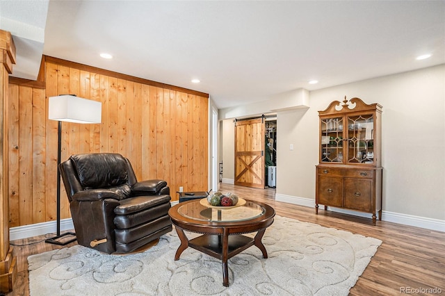 living room with wood walls, a barn door, wood finished floors, and recessed lighting