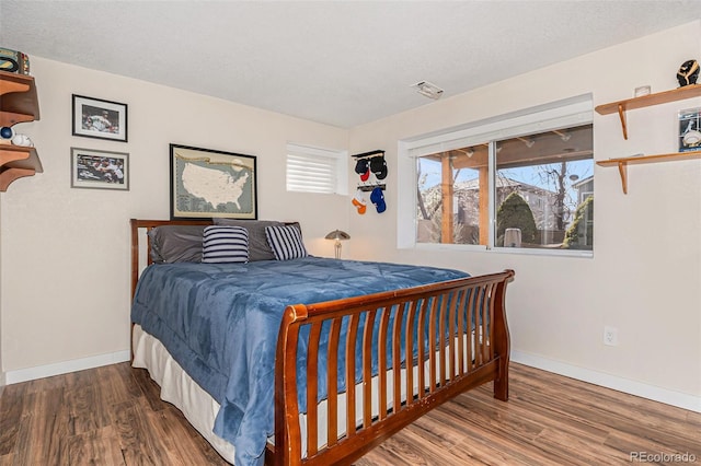 bedroom featuring a textured ceiling, wood finished floors, and baseboards